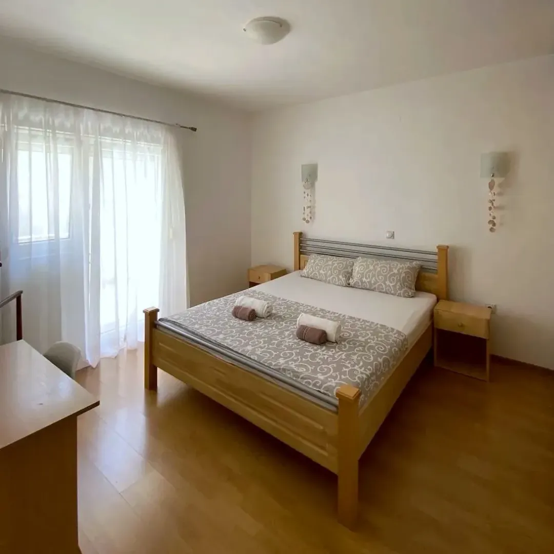 Bedroom with a double bed, wooden furniture, and access to the terrace.