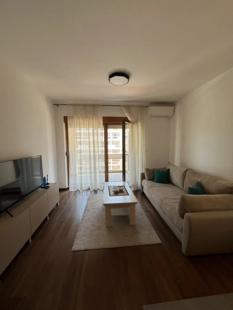 Svijetla dnevna soba sa garniturom i izlazom na balkon.