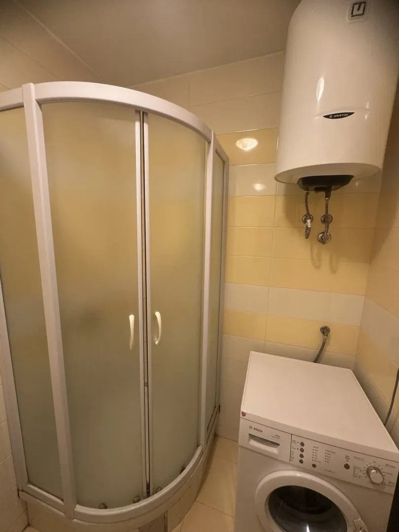 A bathroom with a shower cabin and washing machine.
