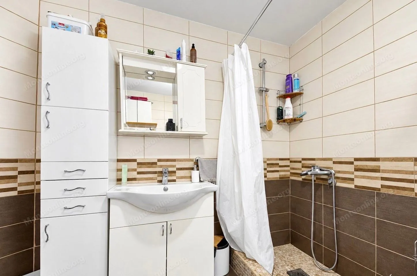 Compact bathroom with a sink, white cabinet, and shower area.