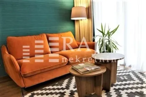 Living room with an orange sofa and wooden coffee tables. - image 2