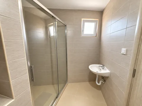 Manje kupatilo obloženo keramičkim pločicama sa tuš kabinom i umivaonikom. - image 8