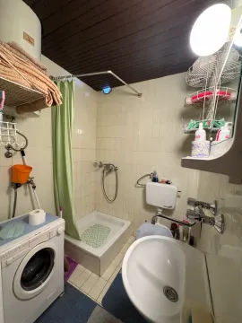 Smaller bathroom with a shower cabin, washbasin, and washing machine. - image 6