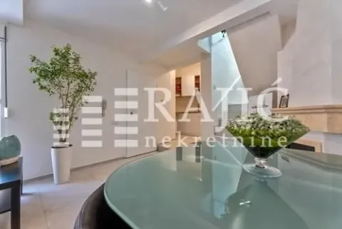 Living room with a dining table and stairs in the background. - image 2