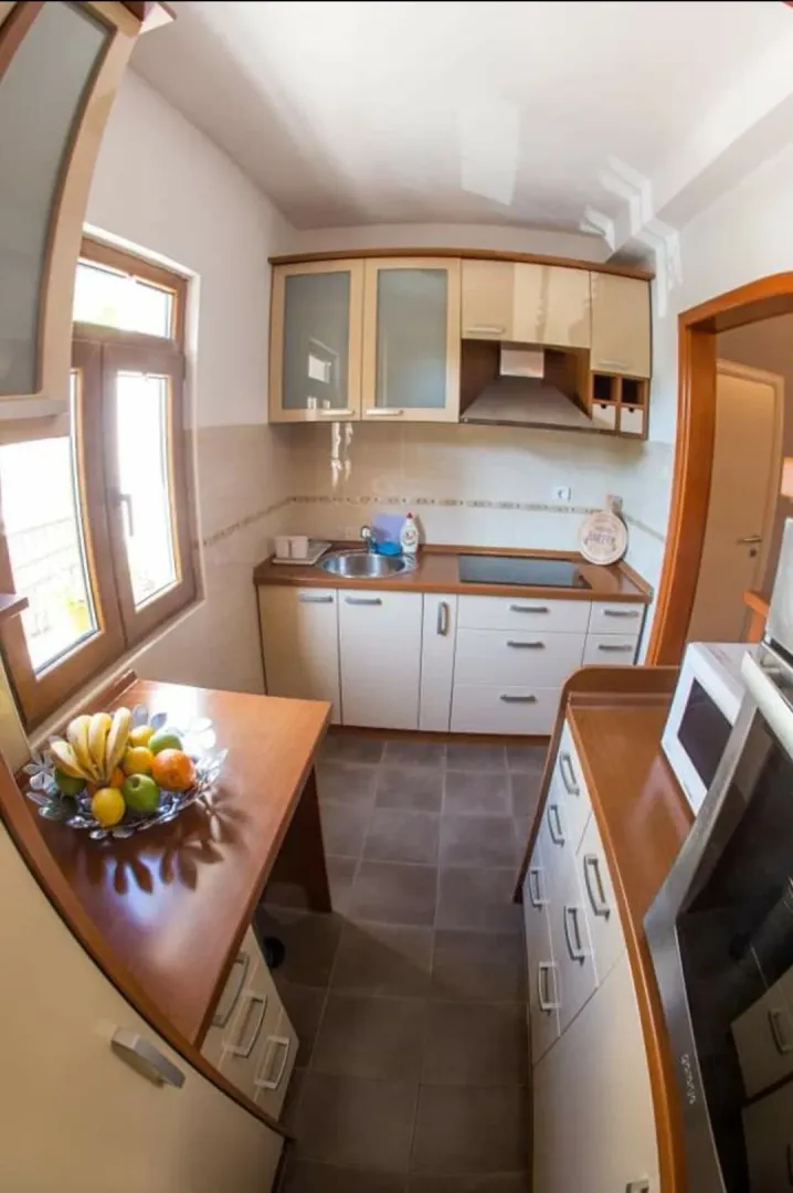 Compact equipped kitchen with wooden cabinetry and a dining table.