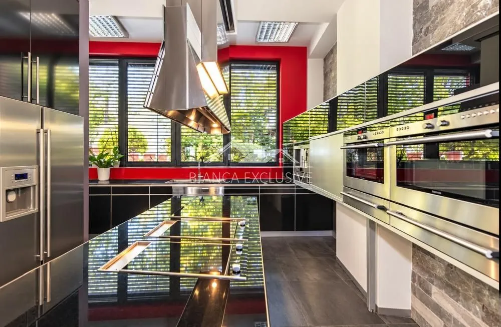 Modern kitchen with dark cabinets, a central island, and built-in appliances.