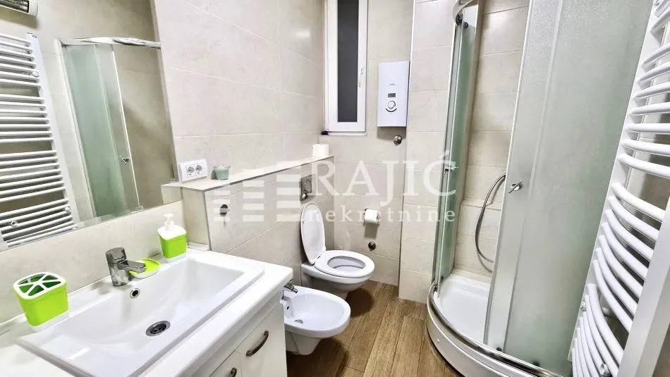 Tidy bathroom with a sink, shower cabin, and sanitary fixtures.