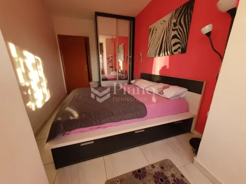 Furnished bedroom with a double bed, wardrobe, and a red accent wall. - image 8