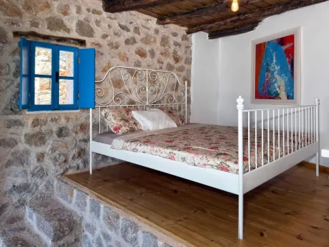 Spavaća soba sa metalnim krevetom i rustičnim kamenim zidom. - image 3