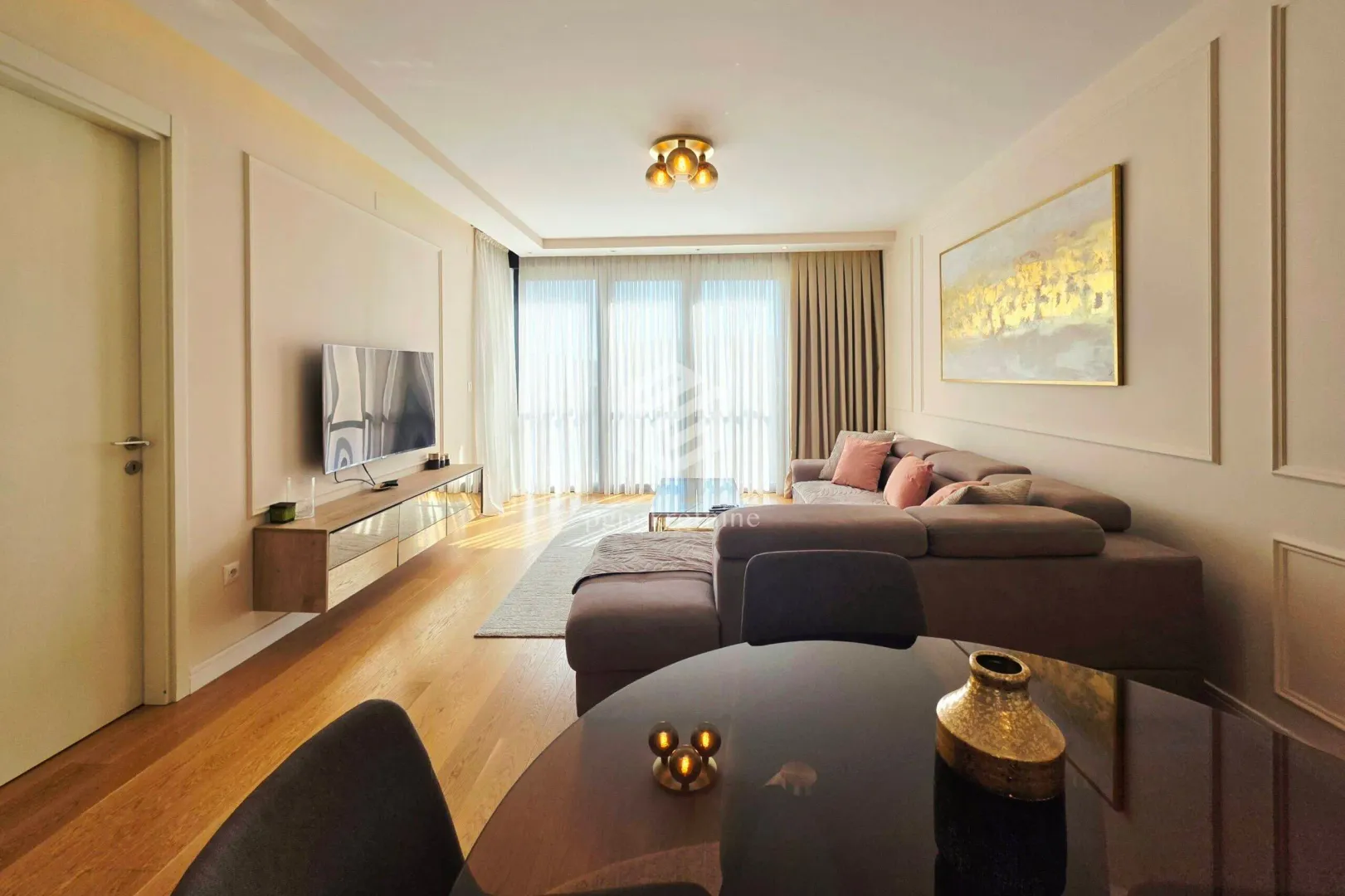 Living room with a sofa, TV, and a dining table in the foreground.