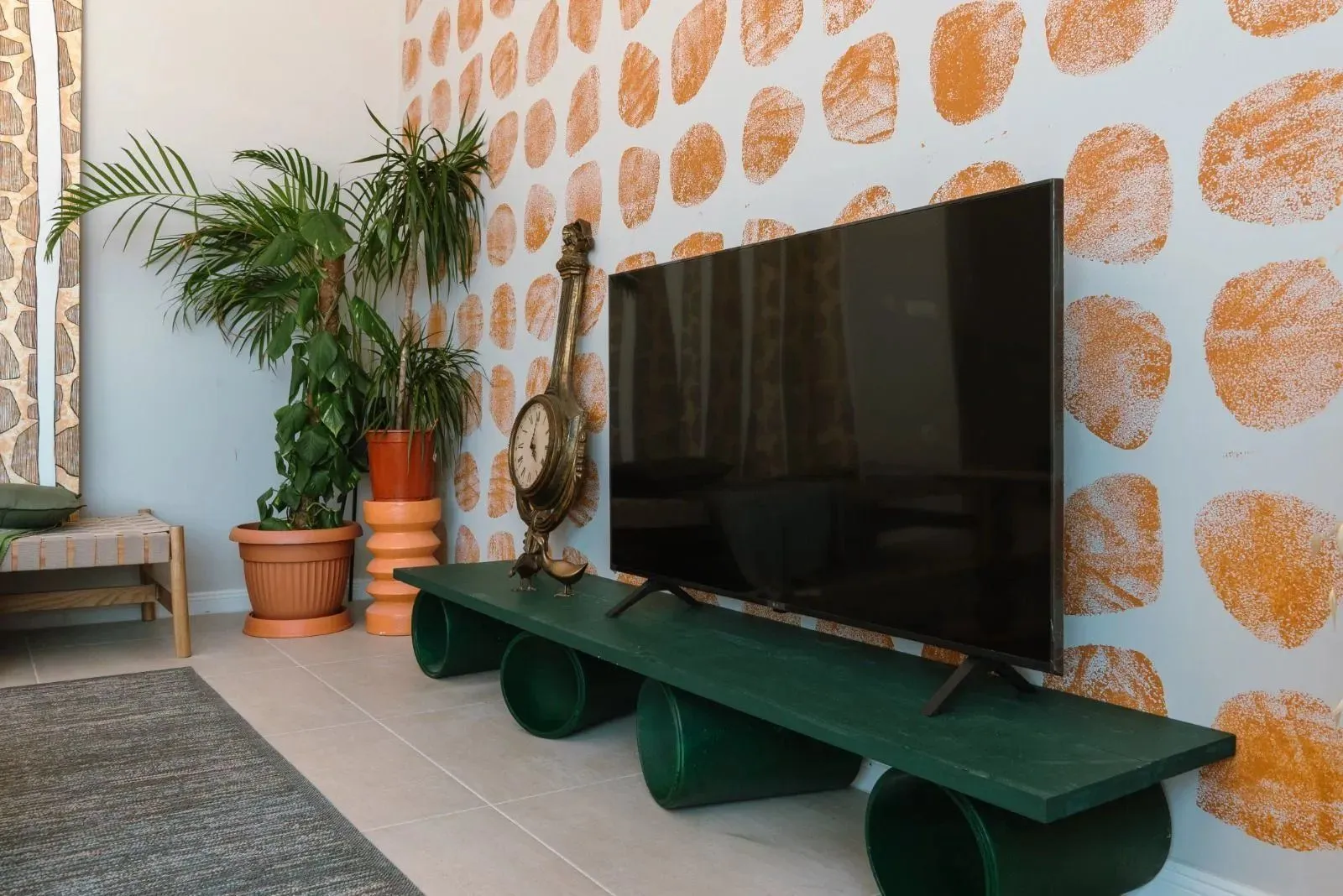 Dnevna soba sa televizorom, dekorativnim zidom i sobnim biljkama.