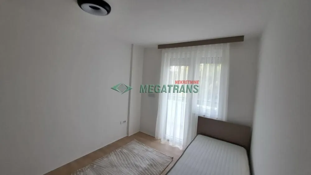 Manja spavaća soba sa krevetom i prozorom prekrivenim zavesama.
