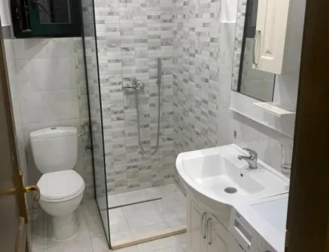 Small bathroom with a walk-in shower, washbasin, and toilet. - image 3