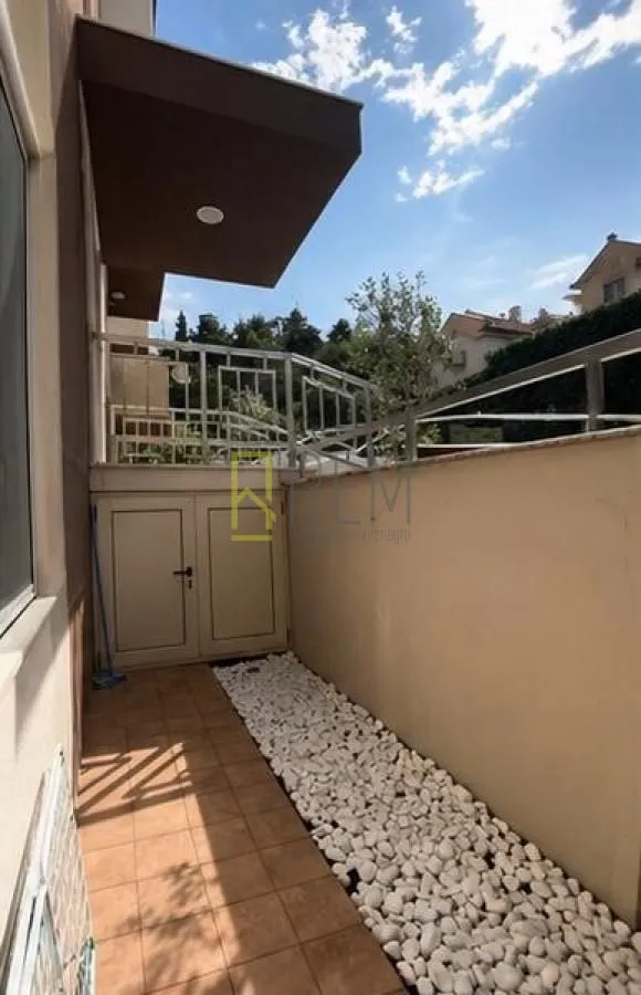Popločani dio dvorišta sa ukrasnim kamenjem ispred ulaza u zgradu.