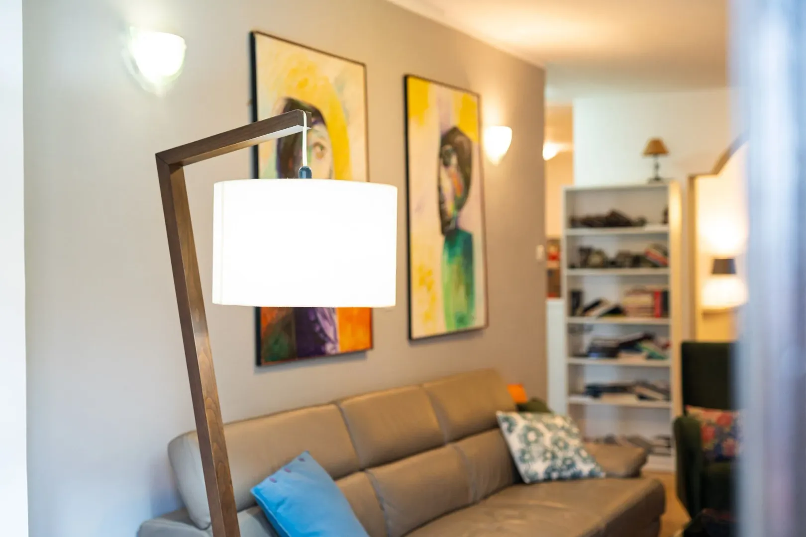 Cozy living room with a leather sofa, floor lamp, and art pieces.