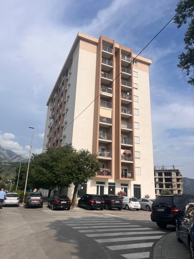 Exterior view of an apartment building with parking in front.