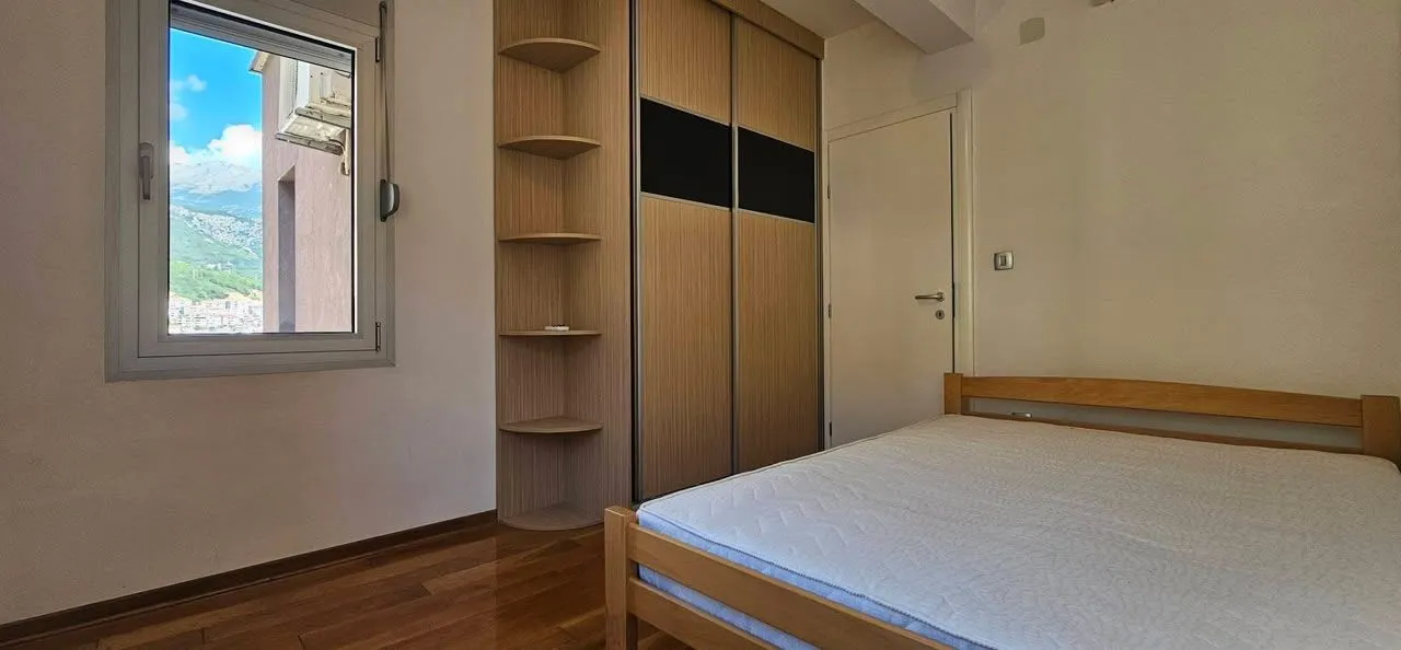 Bedroom with a wooden bed, wardrobe, and a window with mountain views.