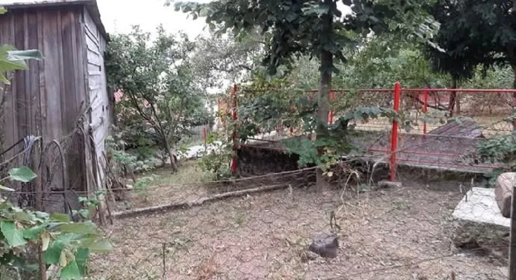 Pogled na dvorište sa pomoćnim objektom i ogradom.