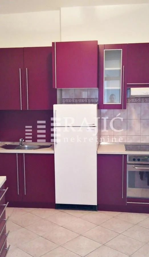 Modern kitchen with purple cabinets and a white refrigerator.