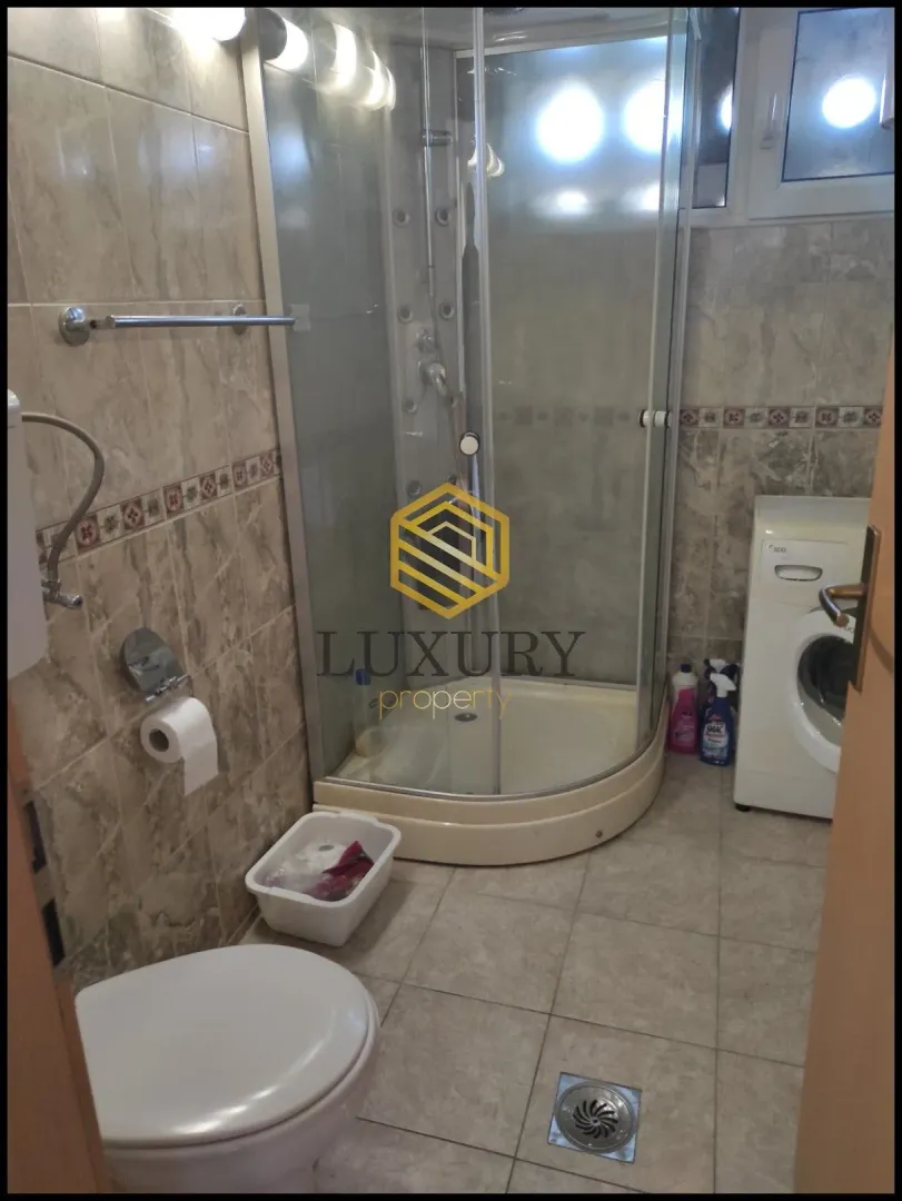 Small equipped bathroom with a shower cabin and washing machine.