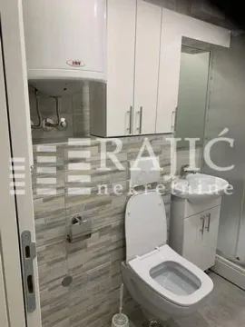 Small bathroom with a toilet, sink, and water heater. - image 9