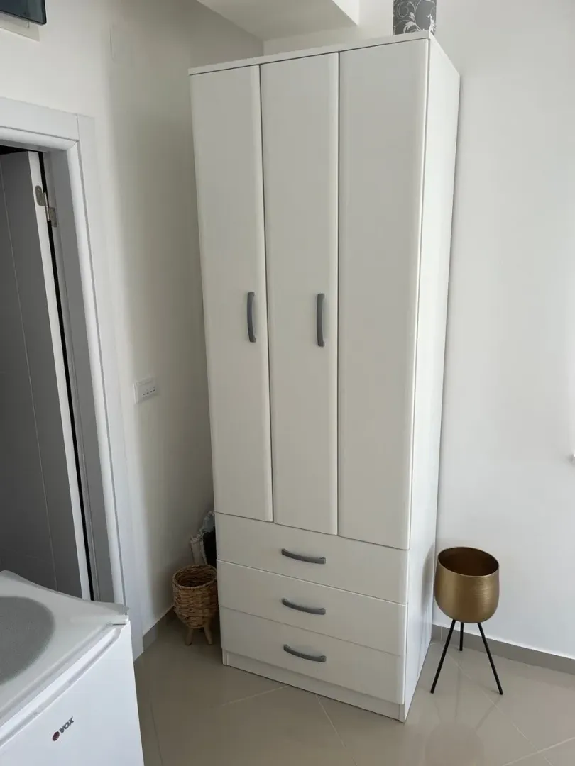 Bijeli garderober u sobi sa bijelim zidovima i pločicama.