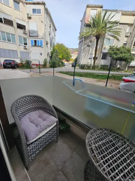 Small furnished balcony with a chair and table and a view of buildings. - image 10