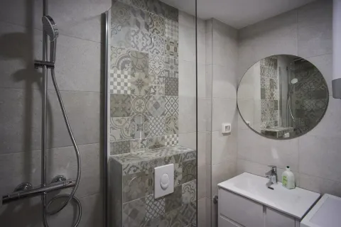 Moderno kupatilo sa tuš kabinom, dekorativnim pločicama i okruglim ogledalom. - image 8