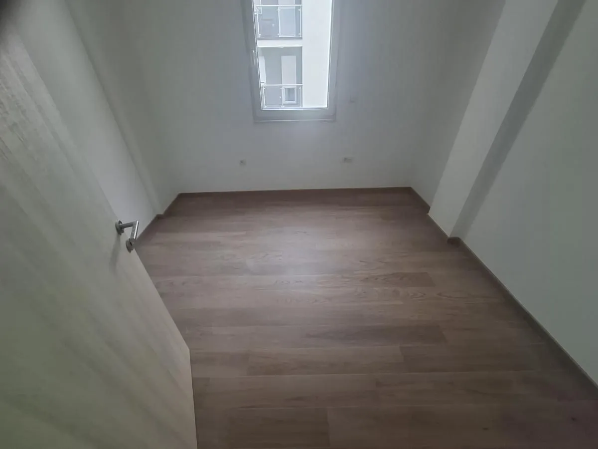 Prazna soba sa laminatom i belim zidovima.