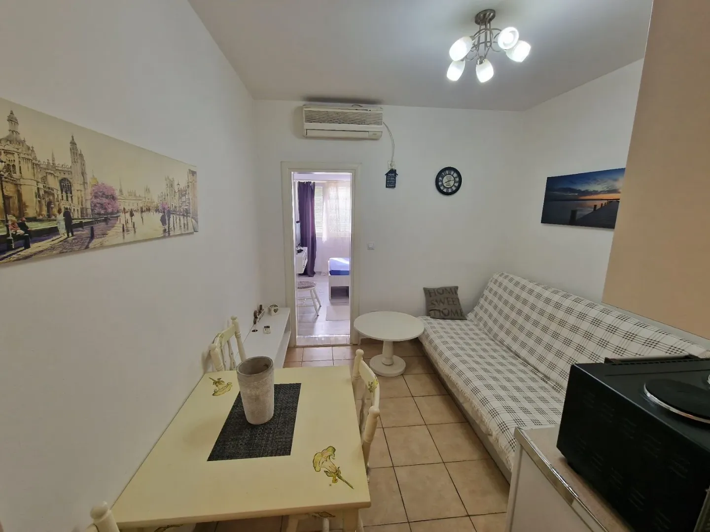 Living room with a sofa, dining table, and a view of the hallway.