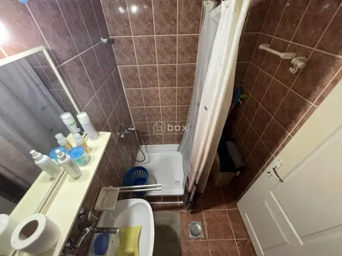 Kupatilo sa tuš kabinom i umivaonikom obloženo braon pločicama. - image 7