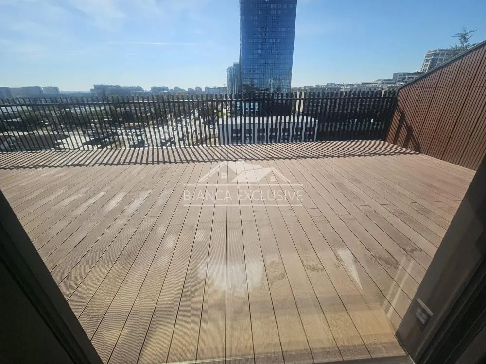 Velika drvena terasa sa ogradom i pogledom na grad.