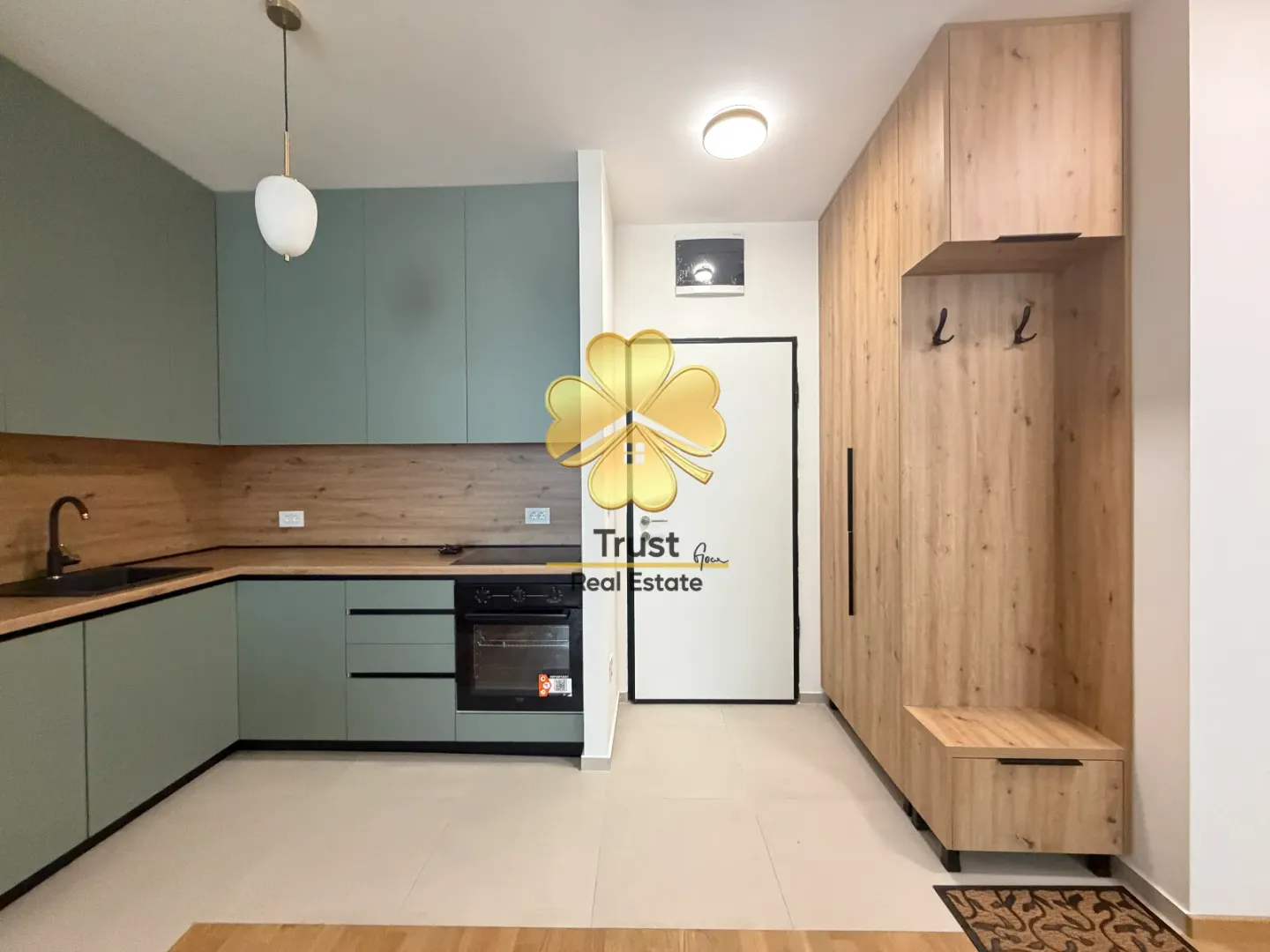 Modern green kitchen with wooden elements and a built-in hallway wardrobe.