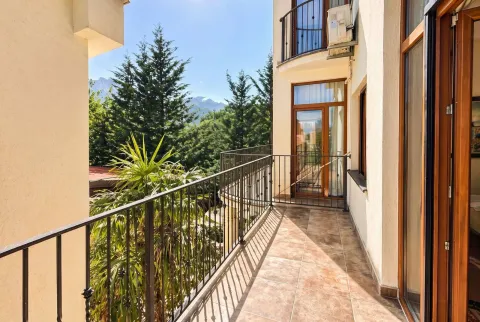 Spacious balcony with metal railing and view of greenery and mountains. - image 9