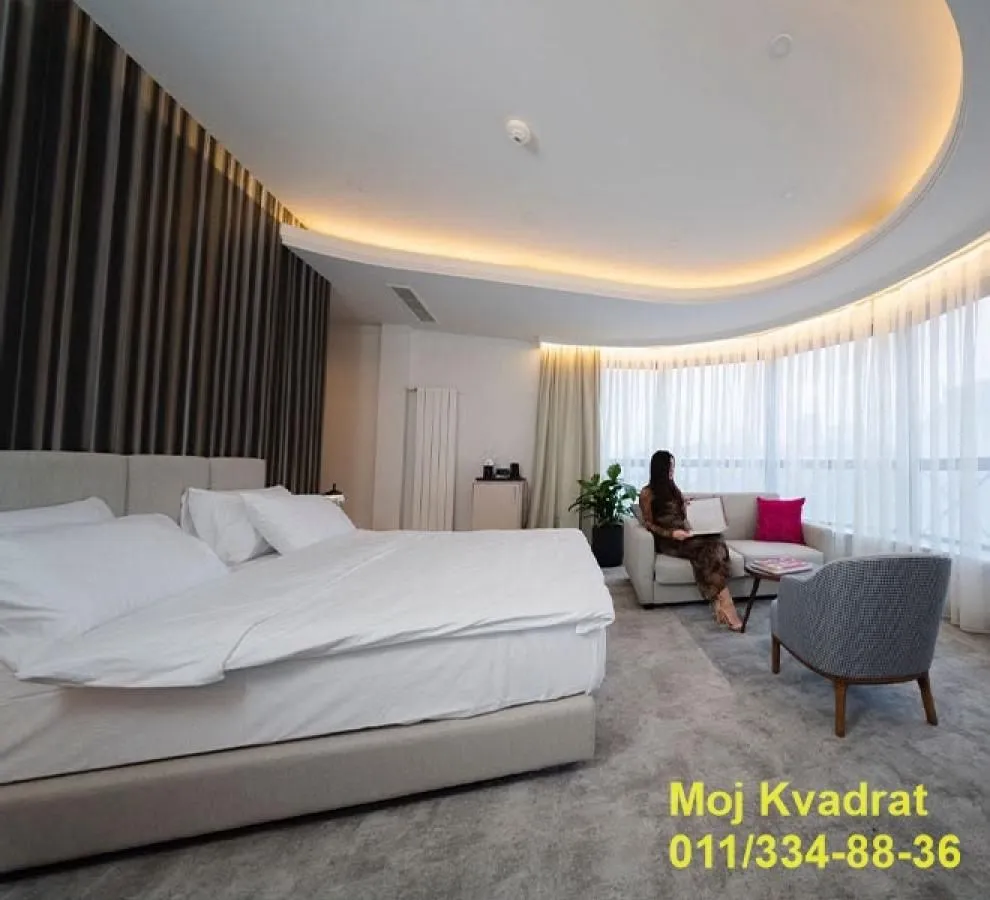 Spacious bedroom with a large double bed and a seating area by the window.