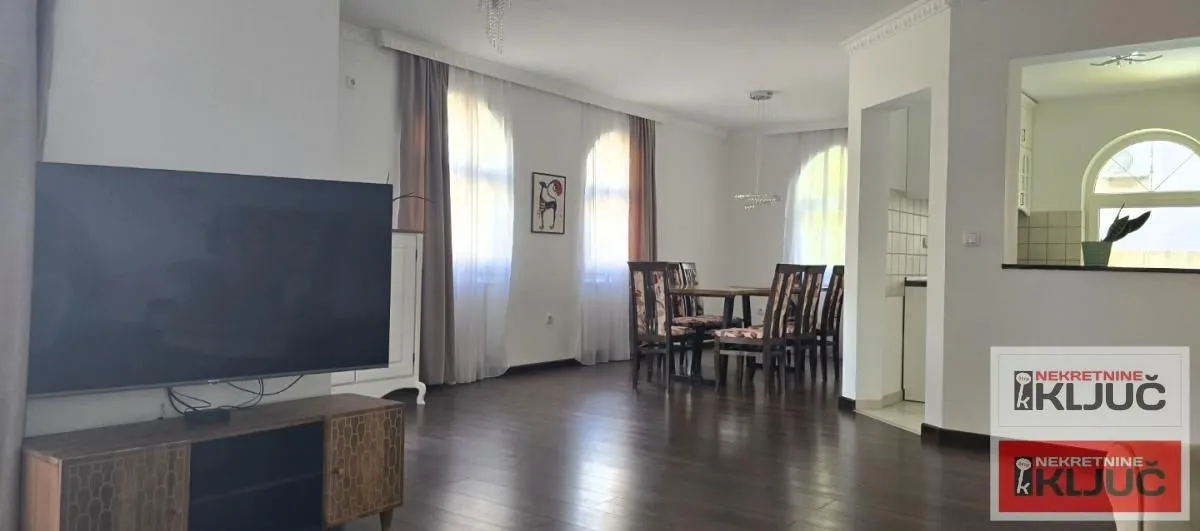 Spacious living room with a TV, dining area, and a view of the kitchen.