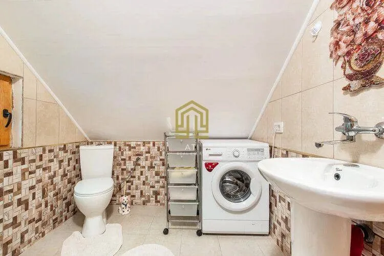 Small bathroom with a toilet, washbasin, and washing machine.