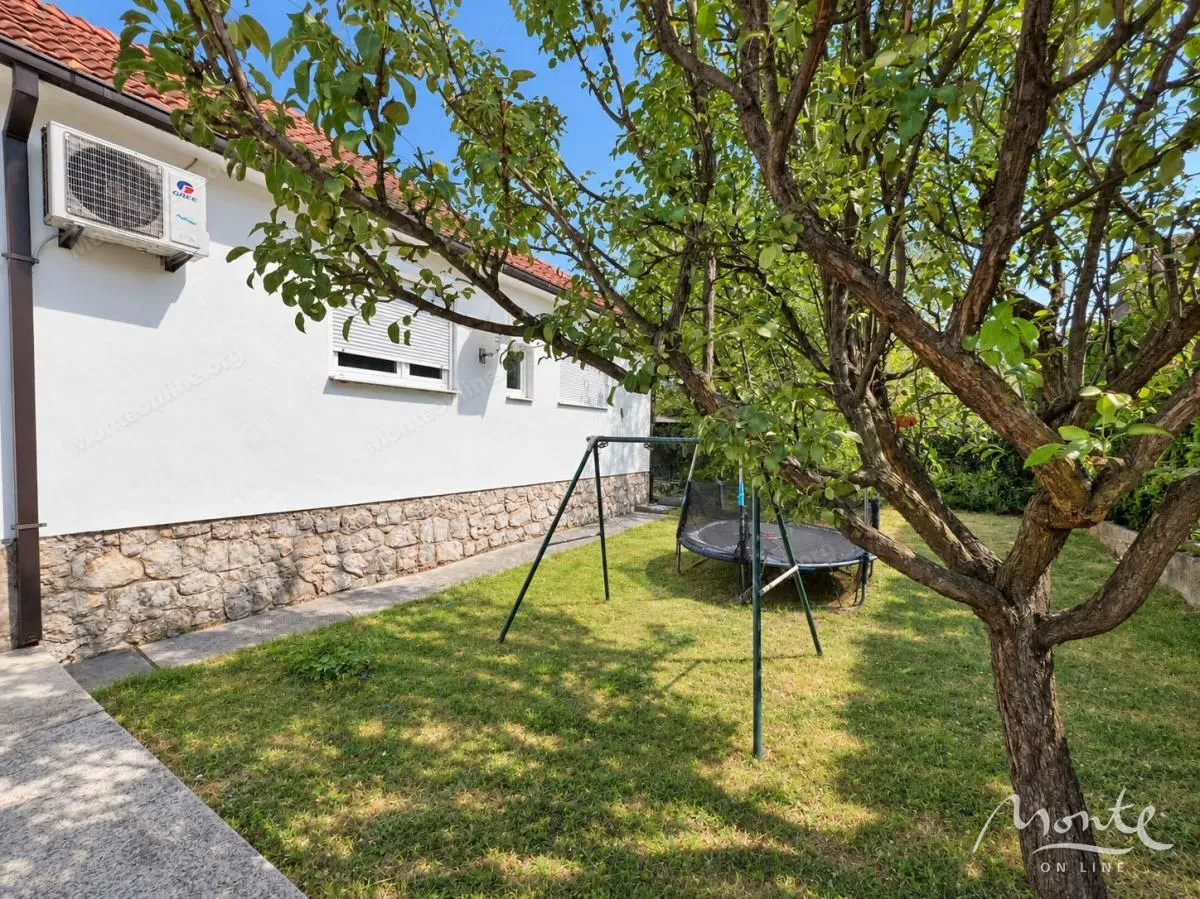 Dvorište kuće sa travnjakom, drvećem i dječijom ljuljaškom.