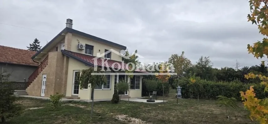 Pogled na spoljašnjost kuće sa dvorištem i zelenilom.