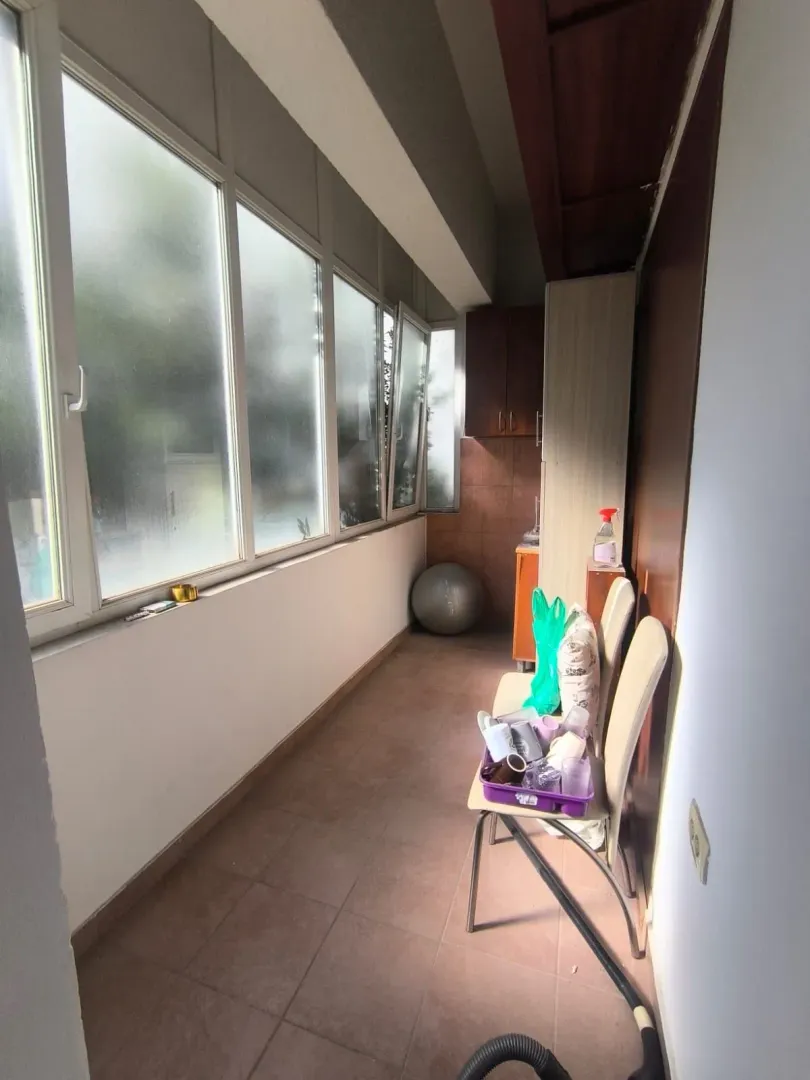 Enclosed balcony with chairs and clutter.
