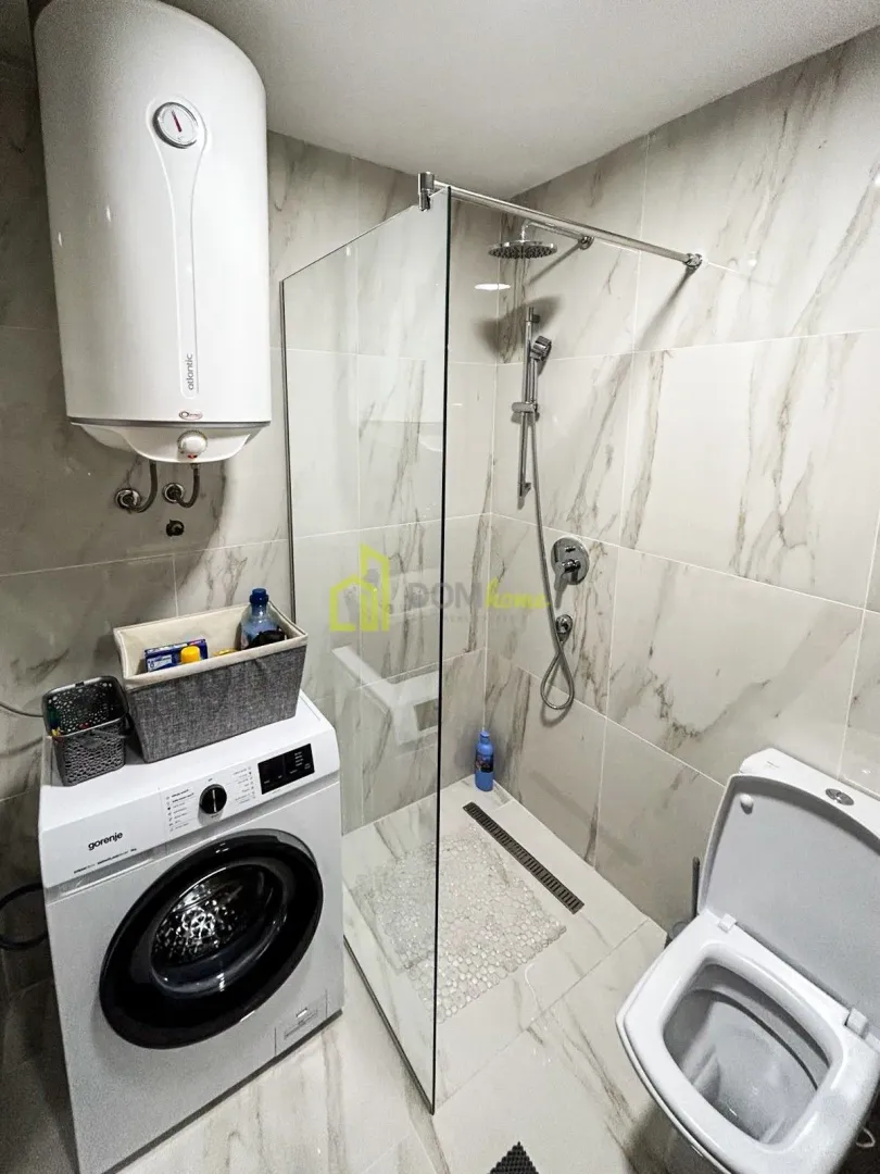 Bathroom equipped with a walk-in shower, toilet, water heater, and washing machine.