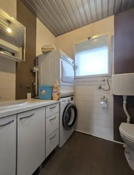 Kupatilo opremljeno umivaonikom, WC šoljom i mašinama za pranje i sušenje veša. - image 8