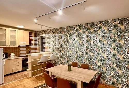 Modern kitchen with dining area and decorative wallpaper on the wall.