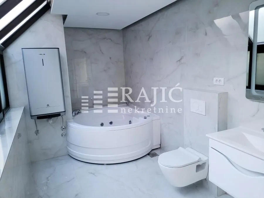 Modern bathroom equipped with a corner bathtub, washbasin, and sanitary fixtures.
