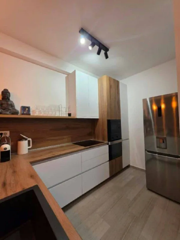 Modern kitchen with white cabinetry, wooden countertops, and built-in appliances.