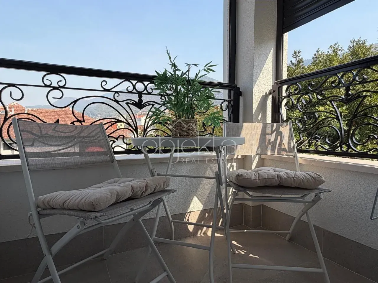 Furnished balcony with a table, chairs, and a decorative plant.