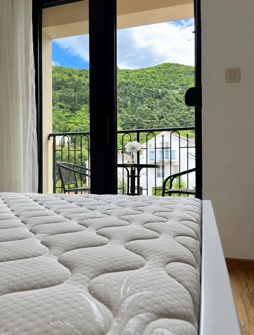 Spavaća soba sa pogledom na balkon i zelena brda.