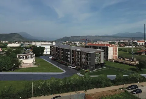 Pogled iz vazduha na stambenu zgradu sa okolnim uređenim dvorištem i parkingom. - image 8