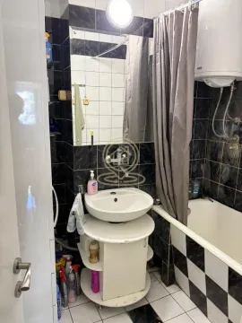 Smaller bathroom with a washbasin, bathtub, and water heater. - image 12
