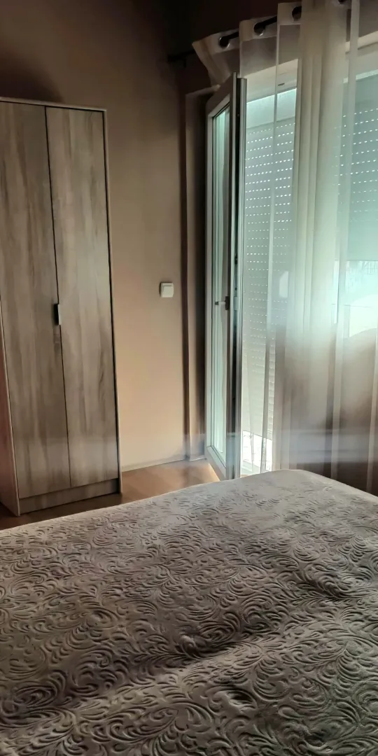 Furnished bedroom with a double bed, wardrobe, and balcony door.